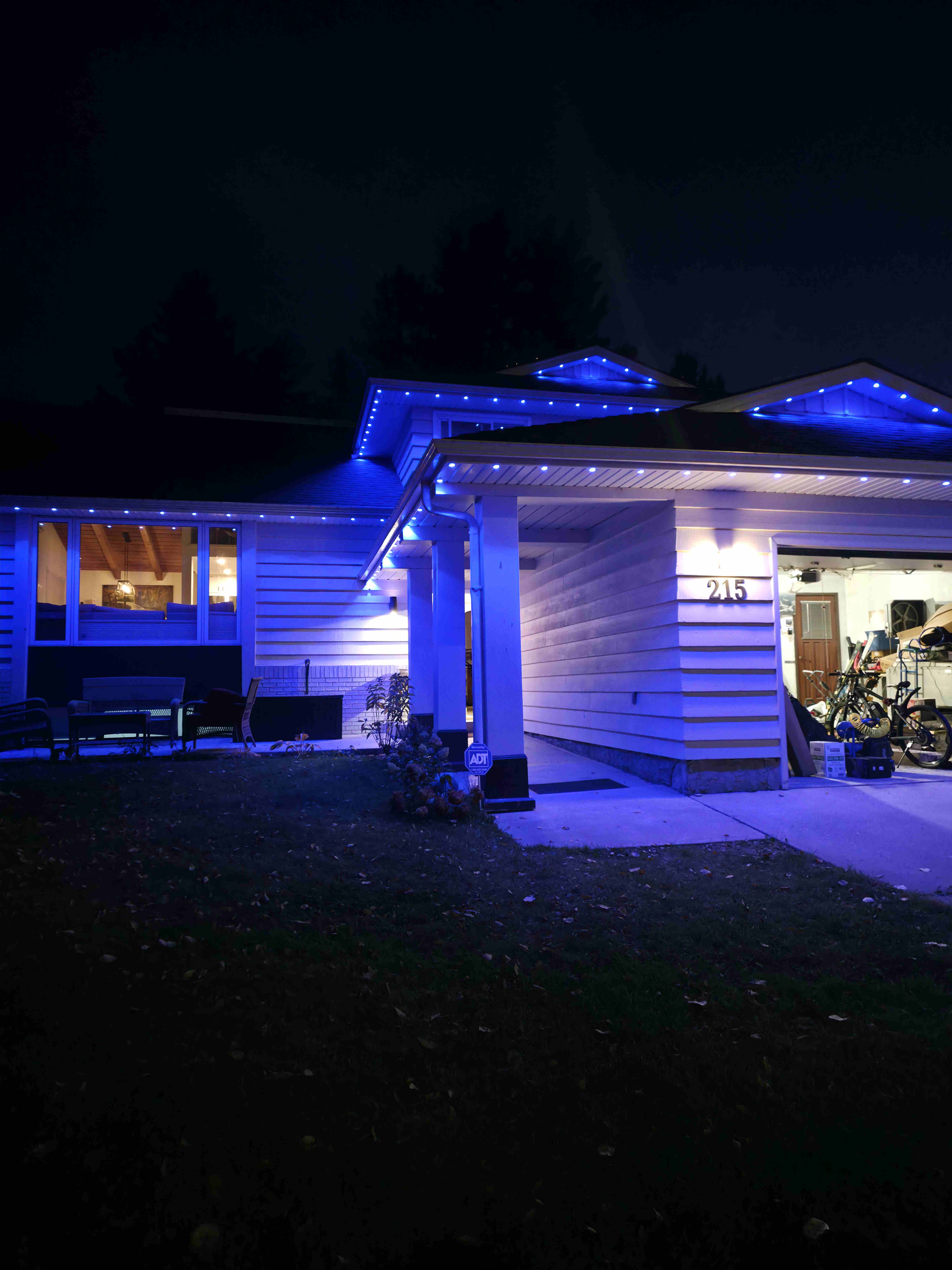 Bungalow with blue permanent lights along the eaves, gables and front entry