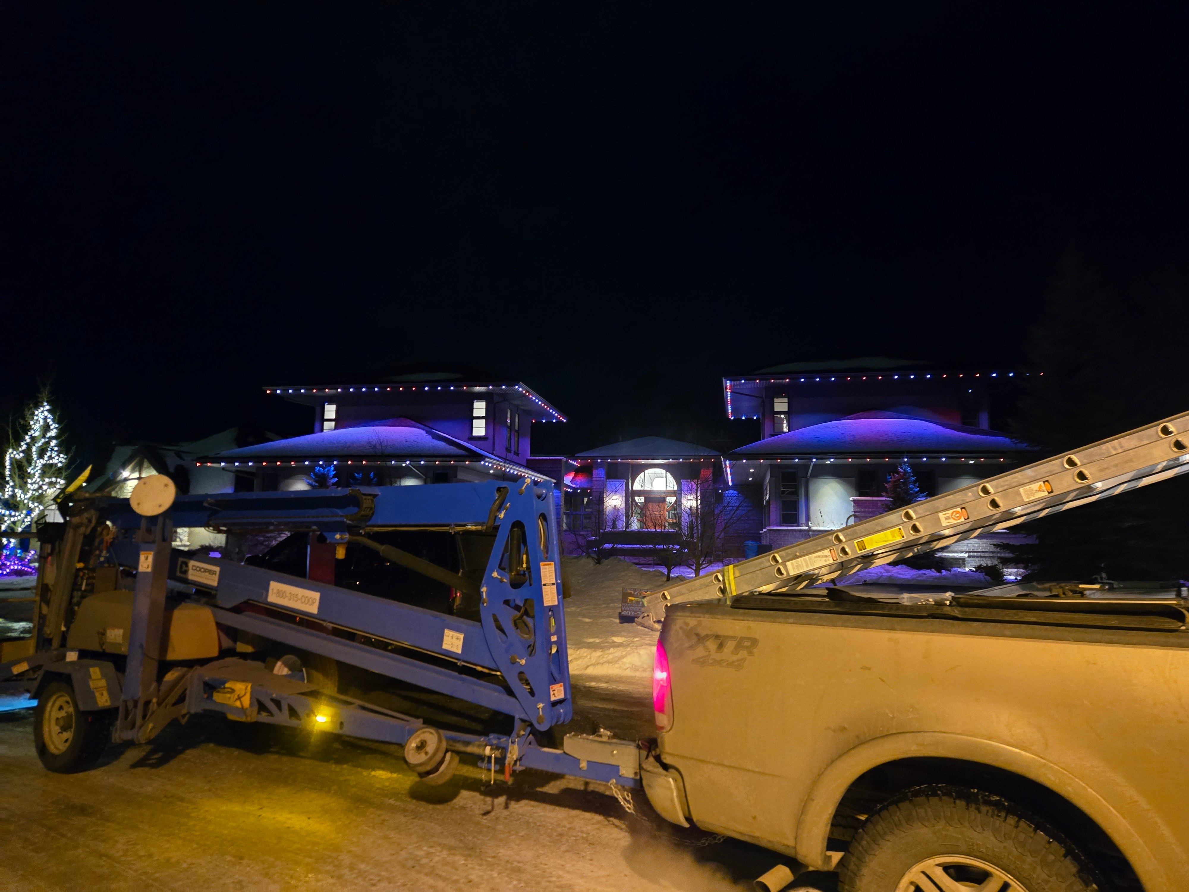 Govee Calgary crew installing red, white and blue lights from a bucket lift at night