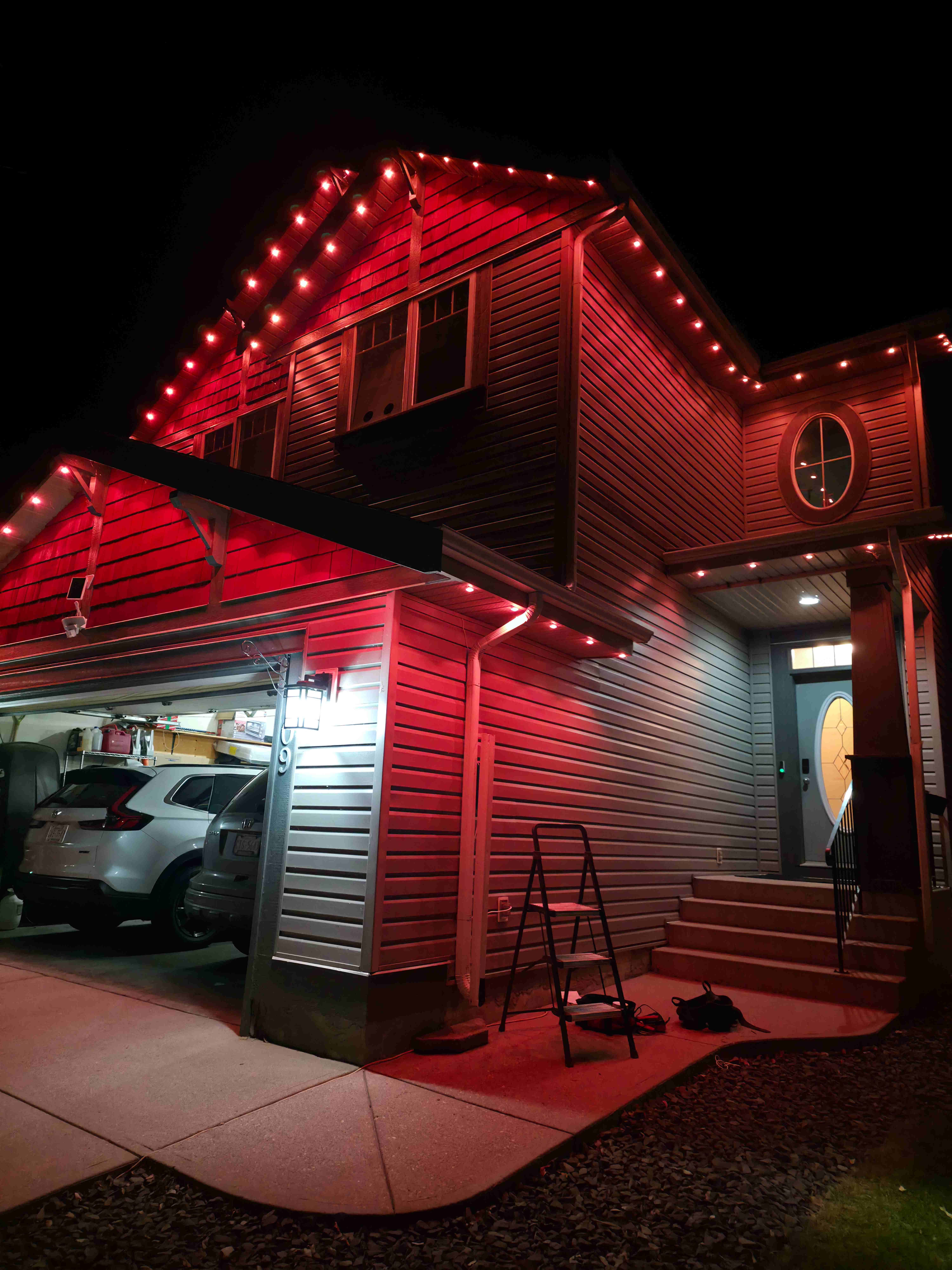 Two-storey home glowing red along every gable and the garage roofline