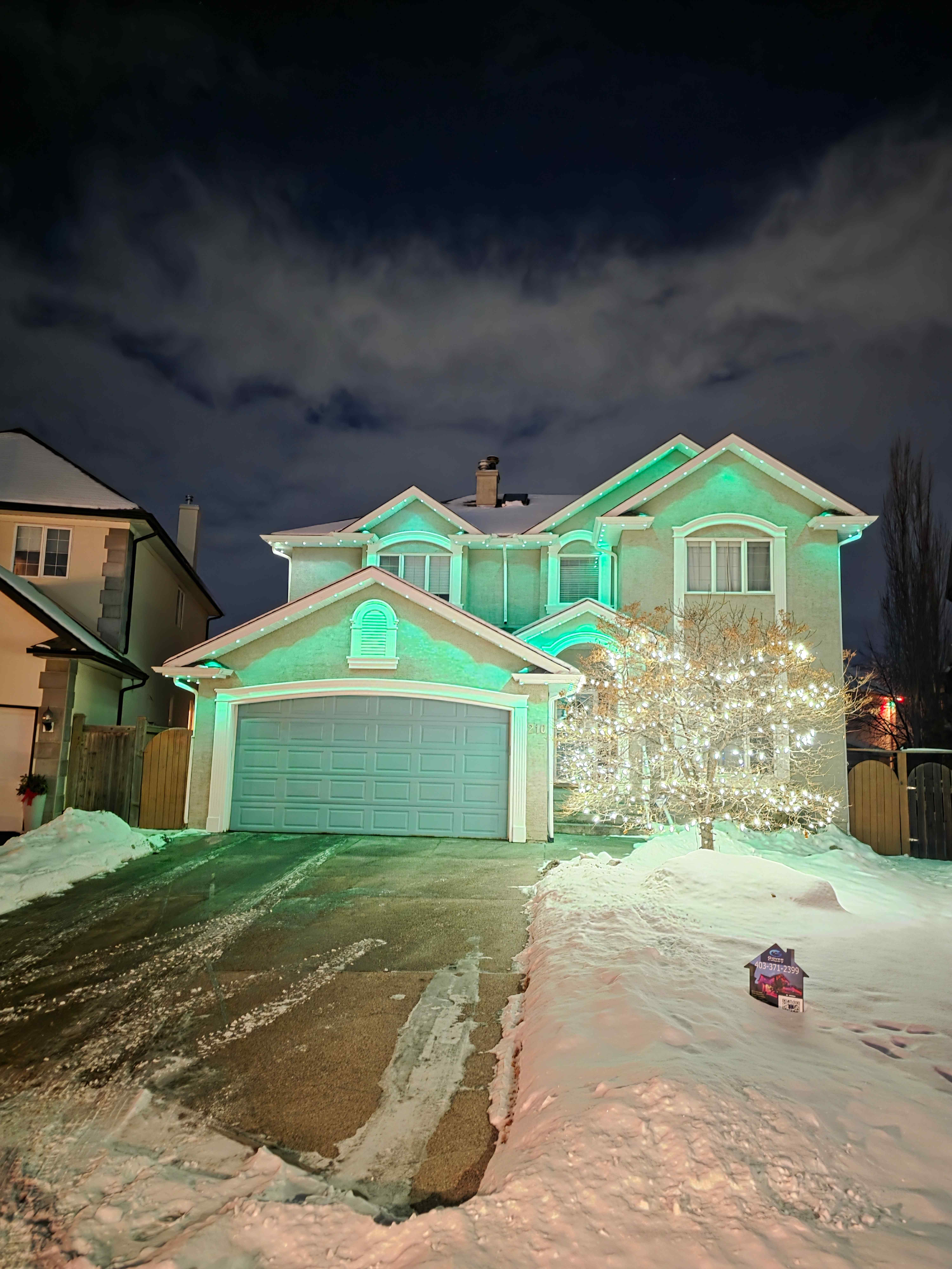 A Govee Calgary install glowing teal over fresh snow with the company yard sign in the foreground